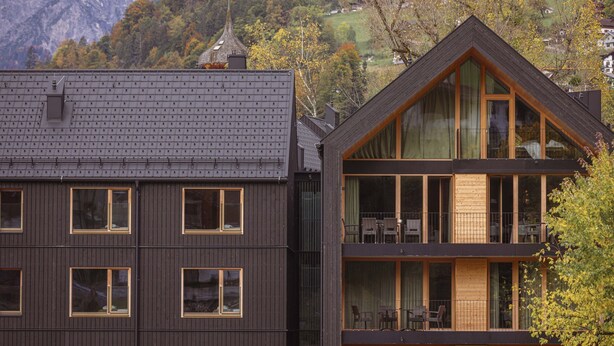 Un edificio moderno con fachada oscura, ventanas amplias y una llamativa estructura de techo triangular.