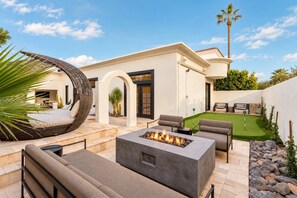 Eine moderne Außenpatio mit Feuerstelle, Sitzgelegenheiten und einem gepflegten Rasen.