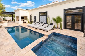 Ein Schwimmbad mit Whirlpool, Liegestühlen und einer Terrassenanlage mit Gartenmöbeln.