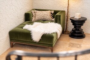 A green upholstered sofa with a fluffy white throw blanket and a textured beige pillow.