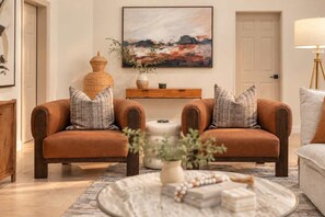 A living room with two brown sofas, a round coffee table, and a painting on the wall.