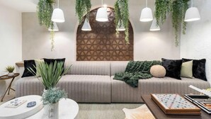 A modern living room with a sectional sofa, hanging plants, pendant lights, and a chessboard. - Casa Del Sol Luxe Experience - Walkable 2 Old Town (Paradise Valley)
