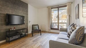 A modern living room with a flat-screen TV, a sofa, and a chair.
