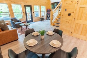 Een gezellig cabin interieur met een ronde eettafel gedekt voor vier personen, een bank en een trap naar een hoger niveau.