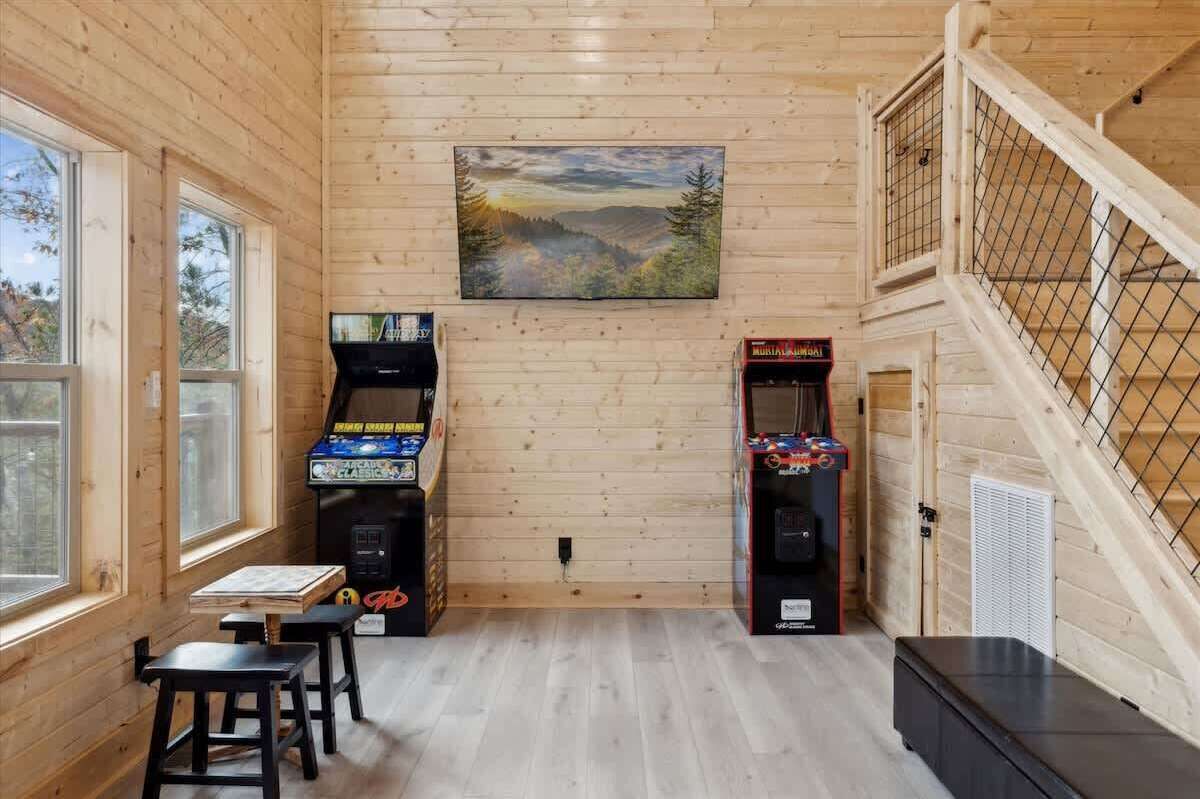 Een houten interieur met flipperspelletjes, een schilderij en een trap.