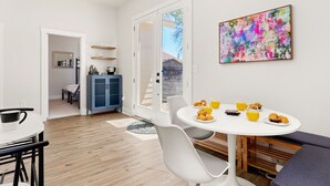 A modern kitchen with a dining area, a large window, and a colorful abstract painting on the wall. - Stylish Home Nr DT, Alamo, River Walk | Games WiFi (San Antonio)
