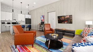 A modern living room with a sofa, armchairs, a coffee table, and a TV. - Stylish Home Nr DT, Alamo, River Walk | Games WiFi (San Antonio)