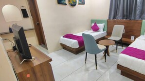 Quarto de hotel com duas camas, uma escrivaninha com computador, uma cadeira e uma pequena mesa.