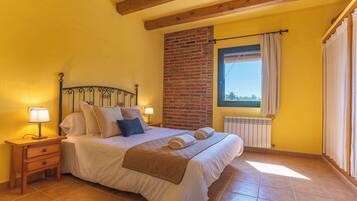 A bedroom with a bed, nightstands, a window with curtains, and a brick wall.