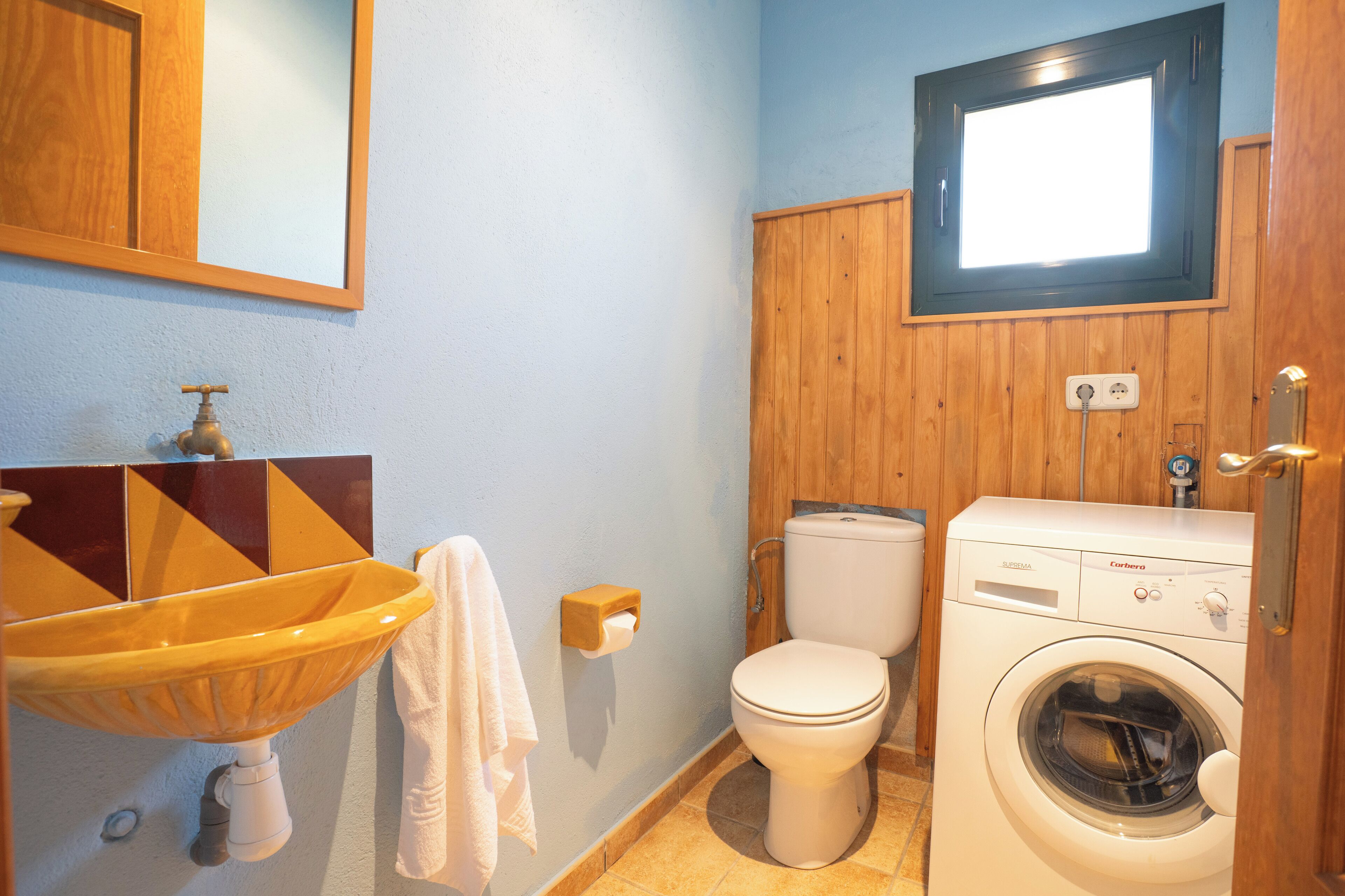 Un baño con lavamanos, inodoro y lavadora de madera.