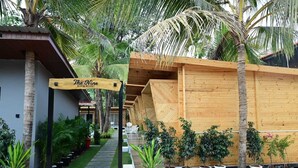 Ein Resort mit Holzstruktur, einem Schild mit der Aufschrift 'The Nine Beach Resort' und einem mit Kübelpflanzen gesäumten Weg.