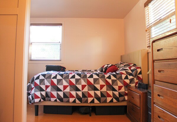 A bedroom with a bed, a dresser, a window, and a door.