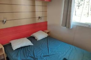 A single bed with a red headboard, two pillows, and a wooden nightstand. - Super Mercure (5 people)   (La Boissière-de-Montaigu)