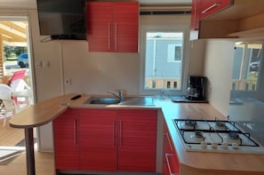 A compact kitchen with a gas stove, a sink, and red cabinets. - Super Mercure (5 people)   (La Boissière-de-Montaigu)