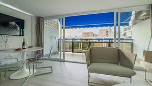 Una sala de estar moderna con una mesa de vidrio, un sofá y un televisor montado en la pared.