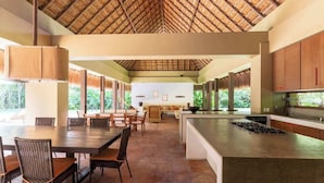 Una cocina amplia con una isla grande, armarios de madera y techo de paja.