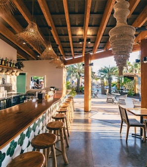 Relax with a drink at the bar, surrounded by comfortable seating and a view of the outdoor pool area.