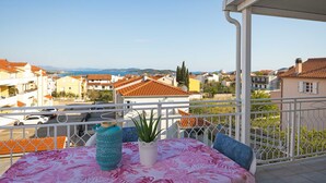A balcony with a table and chairs, a potted plant, and a view of the cityscape and sea. - Studio Apartment Anna Vodice (Vodice)
