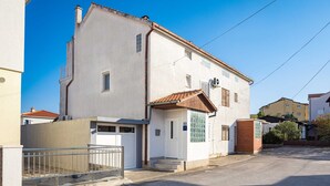 A two-story building with a white facade, a small front porch, and a tiled roof. - Studio Apartment Anna Vodice (Vodice)