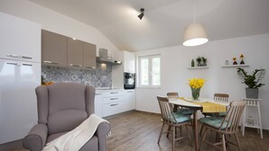 Eine moderne Küche mit weißen Schränken, einem eingebauten Ofen und einem Essbereich mit Tisch und Stühlen.