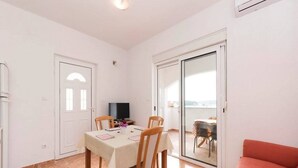 A dining area with a table set for four, a television, and a sliding glass door leading to a balcony.