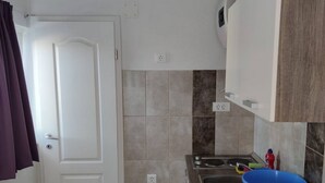 Una pequeña cocina con un lavabo, una pileta azul y un rollo de toallas de papel.