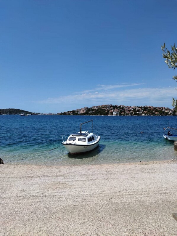 A boat docked on a clear beach with a town in the background.