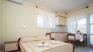 Une chambre avec un lit, une table de chevet et une petite kitchenette.