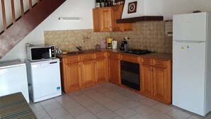 A kitchen with wooden cabinets, a microwave, a refrigerator, a stove, and a sink. - Large villa 10 pers near beach, 5 bedrooms, quiet (Valras-Plage)