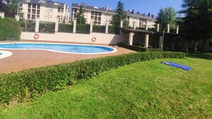 Une piscine entourée d’une pelouse bien entretenue et d’un bâtiment doté de balcons.
