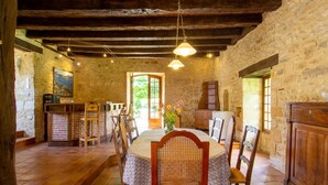 A rustic dining area with a round table, chairs, and a wooden cabinet.
