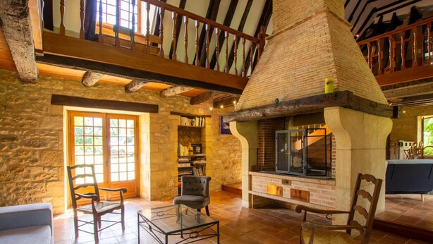 A stone-walled room with a fireplace, wooden furniture, and a bookshelf.