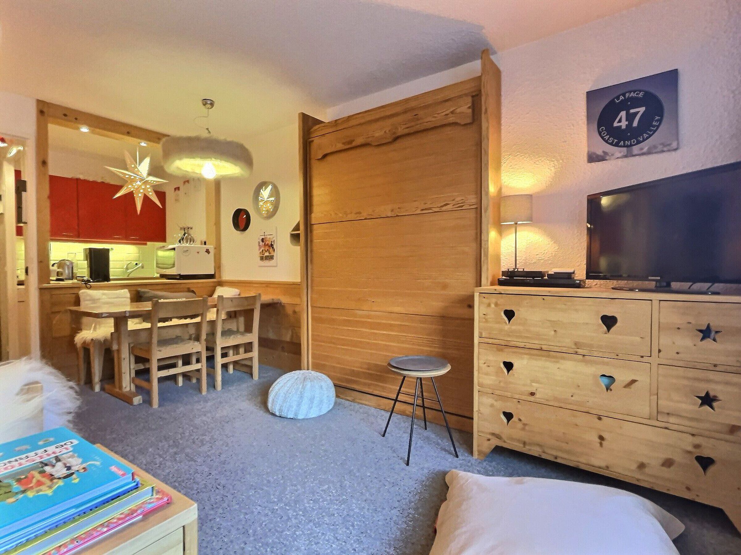 Een gezellige kamer met een houten dressoir, een televisie en een eethoek met een lamp in de vorm van een ster.