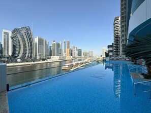 A rooftop infinity pool with a view of a city skyline and a river.