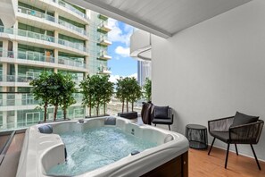 A balcony with a hot tub, two chairs, and potted plants. - Lush Living w jacuzzi and Burj Khalifa view (Dubai)