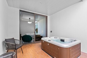 Ein modernes Badezimmer mit einer Badewanne, einer Duschkabine und einer Glastür, die auf einen Balkon mit einem Stuhl und einem Tisch führt.