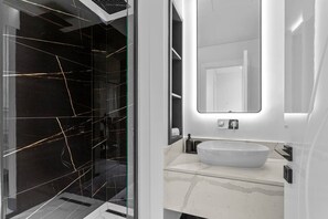 A modern bathroom with a large glass door, a white sink, and a mirror above it.
