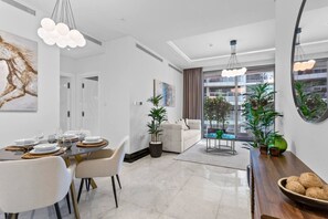 A modern living room with a dining area, large windows, and indoor plants.