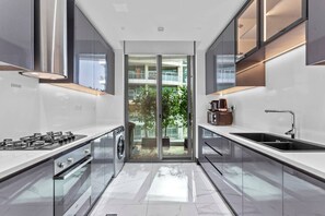 Een moderne keuken met een centraal eiland, roestvrijstalen apparatuur en uitzicht op een balkon.