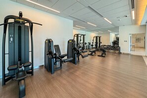 A spacious gym with various exercise machines, including weight benches and free weights, arranged in an open layout.