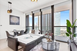 A modern hotel room with a large bed, a dining area, and a view of the cityscape. - Luxury 1 Bedroom in the Heart of Famous Downtown (Dubai)