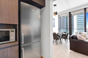 Une cuisine moderne équipée d’un réfrigérateur en acier inoxydable, d’un four à micro-ondes et d’un coin repas avec une table et des chaises.