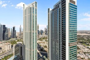 Two high-rise buildings with the name 'EMAAR' on top, surrounded by a cityscape with various other buildings and a clear sky. - Luxury 1 Bedroom in the Heart of Famous Downtown (Dubai)