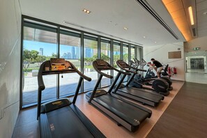 A gym with treadmills, a weight bench, and a person exercising.