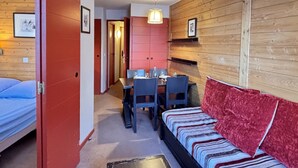 A compact room with a bed, a dining table with chairs, and a sofa.