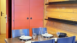 A dining area with a wooden table set for four, blue chairs, and a red cabinet with two doors.