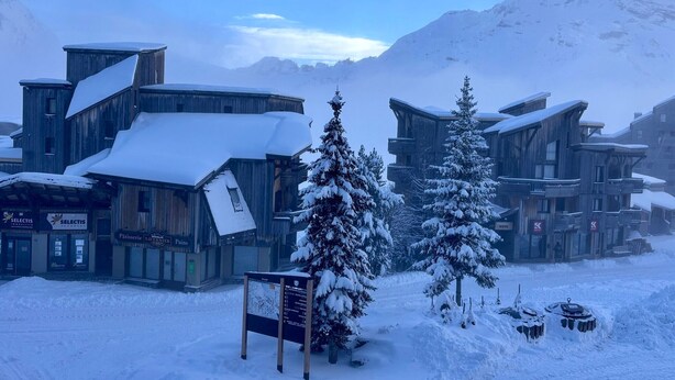 A snow-covered building with a signboard in front.