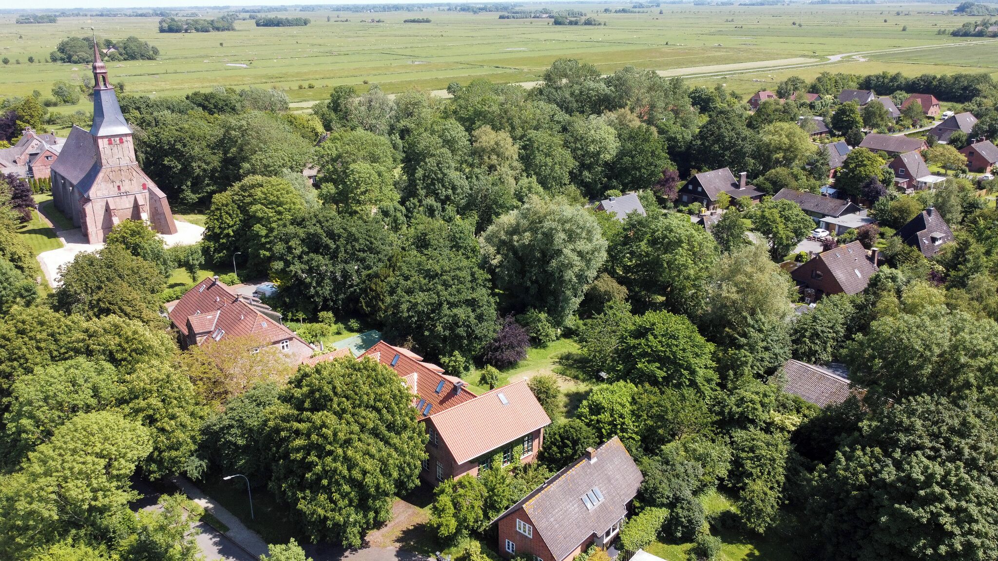 An aerial view of a rural village with a church, houses, and surrounding fields.