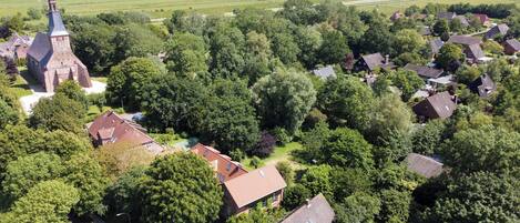 An aerial view of a rural village with a church, houses, and surrounding fields.
