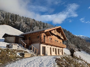 A wooden chalet with a balcony, a staircase, and a view of snow-covered mountains. - Chalet 4 bedrooms, modern comfort, Arêches-Beaufort (Arêches-Beaufort)